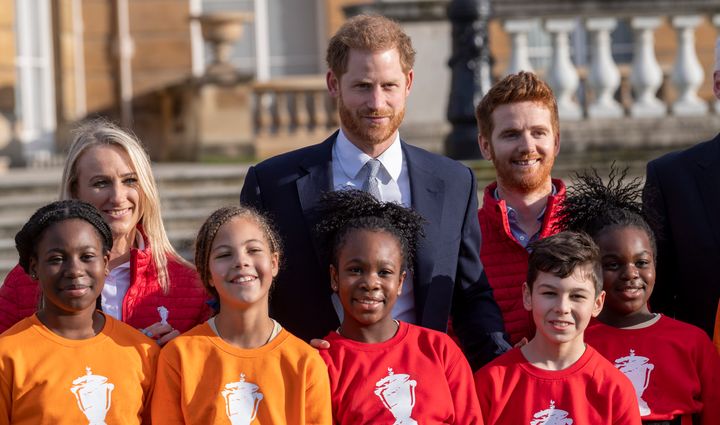Harry poses with children from a local school after watching them play rugby in the Buckingham Palace gardens before the Rugb
