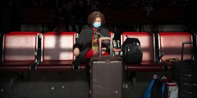 A traveler wears a face mask as she sits in a waiting room at Beijing West Railway Station in Beijing, Tuesday, Jan. 21, 2020.