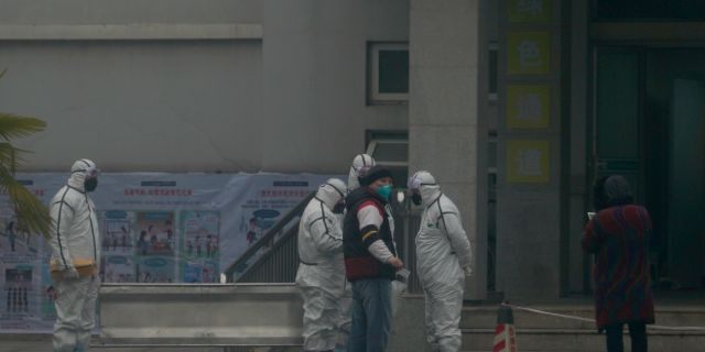 Staff in biohazard suits hold a metal stretcher by the in-patient department of Wuhan Medical Treatment Center, where some infected with a novel coronavirus are being treated.