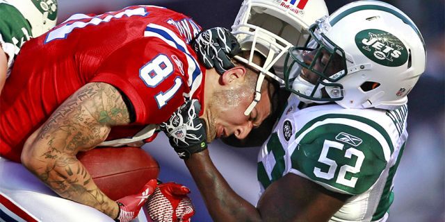 New England Patriots tight end Aaron Hernandez (81) hangs on to the ball as New York Jets inside linebacker David Harris (52) takes off his helmet on a hit during the first half of an NFL football game in Foxborough, Mass., Sunday, Oct. 9, 2011.
