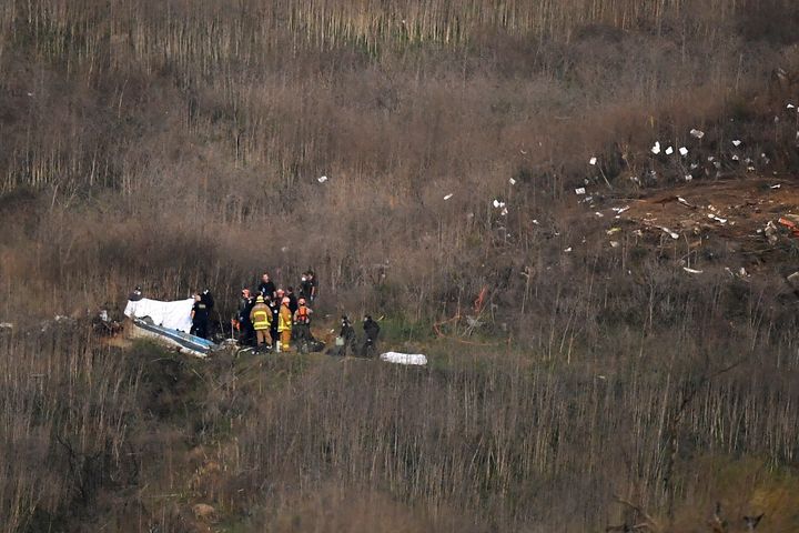 A body is covered, left, while another sits at right at the scene of a helicopter crash that killed former NBA basketball pla
