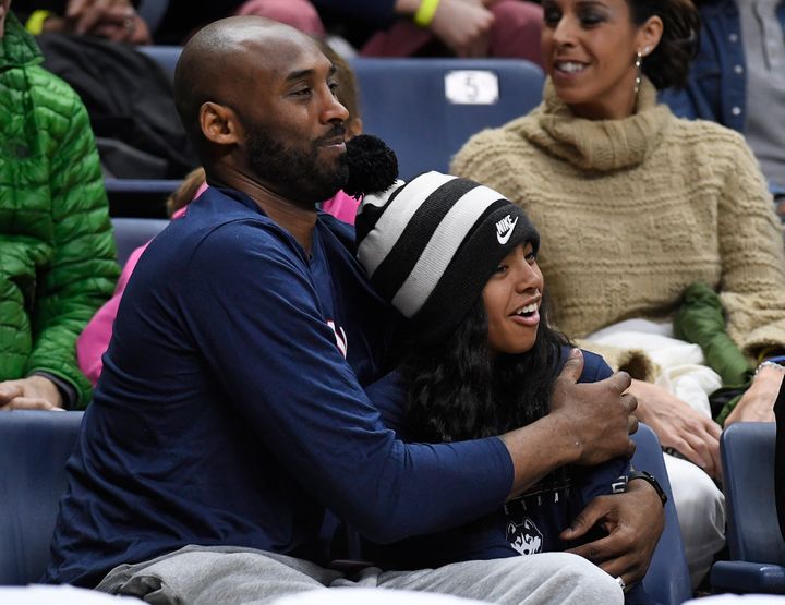 Kobe Bryant and his daughter Gianna watch the first half of an NCAA college basketball game between Connecticut and Houston o