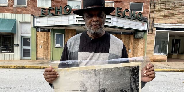 In this Monday, Jan. 13, 2020 photo, Rev. David Kennedy stands outside the Echo Theater holding a photo of his great uncle's lynching, in Laurens, S.C. Kennedy has fought for civil rights in South Carolina for decades. (AP Photo/Sarah Blake Morgan)