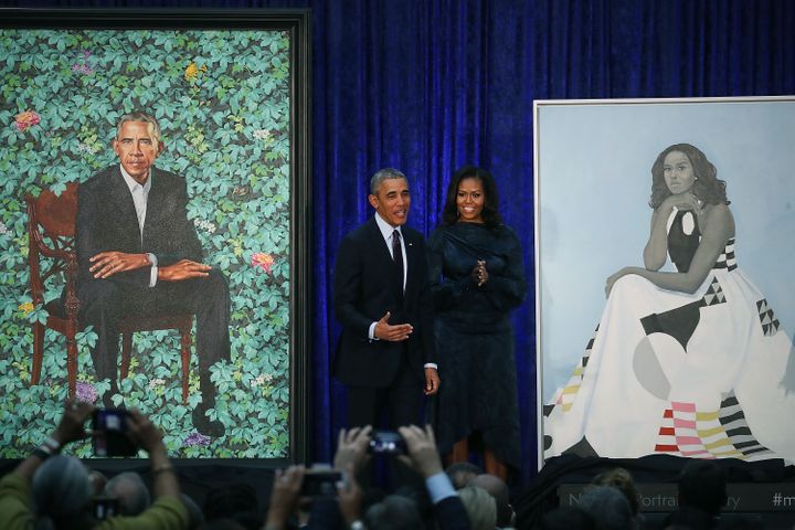 Former U.S. President Barack Obama and former first lady Michelle Obama stand next to their newly unveiled portraits during a