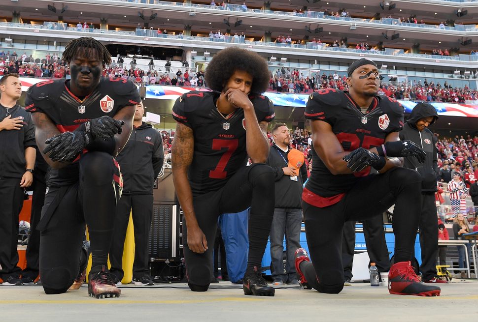 Teammates Eli Harold, Kaepernick and Eric Reid kneel in protest during the national anthem prior to a game against the Arizon