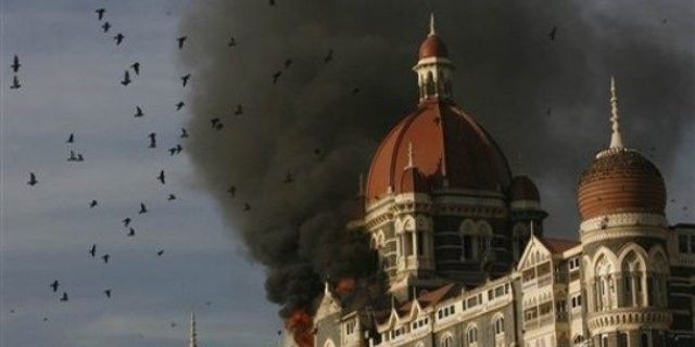 In this Nov. 27, 2008 file photo, pigeons fly as the Taj Hotel continues to burn during terror attacks in Mumbai, India. Indian Prime Minister Manmohan Singh said Tuesday, Jan. 6, 2009, that he did not believe the November Mumbai attacks gunmen were acting alone, and Pakistani state agencies must have had a hand in the attacks. (AP Photo/Gautam Singh, File)