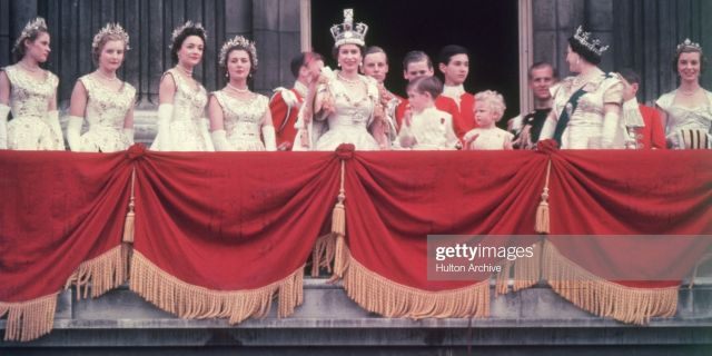 The newly crowned Queen Elizabeth II waves to the crowd from the balcony at Buckingham Palace on June 2, 1953. Her children Prince Charles and Princess Anne stand with her.