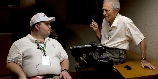 In this image released by Warner Bros. Pictures, director Clint Eastwood speaks with actor Paul Walter Hauser as they work during the filming of the movie "Richard Jewell." 