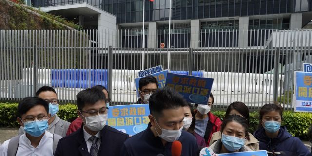 Pro-China supporters wearing masks urge government to deliver masks to local people during a protest in Hong Kong on Tuesday. Hong Kong reported its first death from a new virus, a man who had traveled from the mainland city of Wuhan that has been the epicenter of the outbreak. (AP Photo/Vincent Yu)