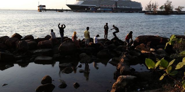 Locals come down to view the Westerdam cruise ship, owned by Holland America Line, docked at the port of Sihanoukville, Cambodia, Thursday, Feb. 13, 2020. The Westerdam, turned away by four Asian and Pacific governments due to virus fears, anchored Thursday off Cambodia for health checks on its 2,200 passengers and crew. (AP Photo/Heng Sinith)