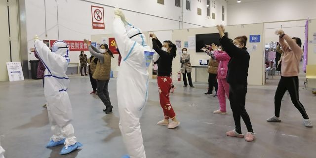 In this Feb. 18, 2020, photo released by Zhang Junjian, medical workers lead patients in exercises at the Wuhan Living Room Temporary hospital in Wuhan in central China's Hubei province. 