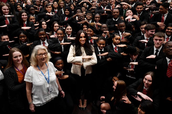 Meghan poses with schoolchildren making the "equality" sign following a school assembly during a visit to Robert Clack School
