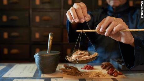 Man measuring ingredients in traditional Asian apothecary. 