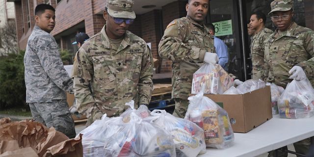 Members of the New York National Guard help to organize and distribute food to families on free or reduced school lunch programs in New Rochelle, N.Y., Thursday, March 12, 2020. State officials have set up a “containment area” in the New York City suburb. (AP Photo/Seth Wenig)