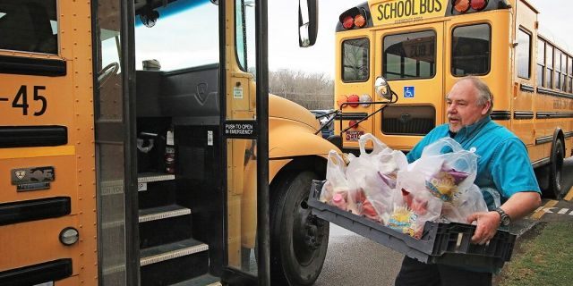 Bus driver Tim Smith loads his bus up with breakfast and lunches for delivery at Ronceverte Elementary on Thursday in Ronceverte, W.Va. Bus drivers will be delivering meals through the rest of the week and volunteers with the Greater Greenbrier Long-term Recovery Committee will be taking over delivery starting Monday. (Jenny Harnish/The Register-Herald via AP)