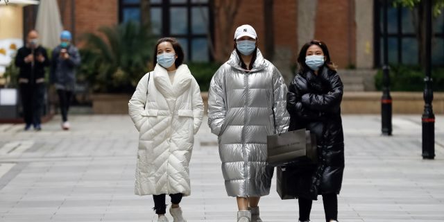 In this photo released by Xinhua News Agency, women wearing protective masks to prevent the new coronavirus outbreak walk on a re-opened commercial street in Wuhan in central China's Hubei province on Monday. (Shen Bohan/Xinhua via AP)