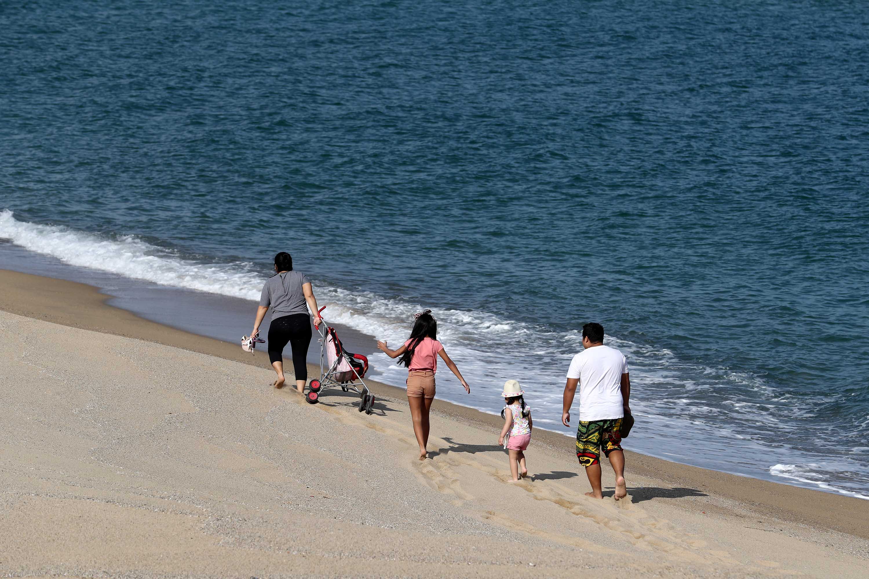A family walks on a beach in Barcelona, Spain, on April 26, after some lockdown restrictions were lifted.