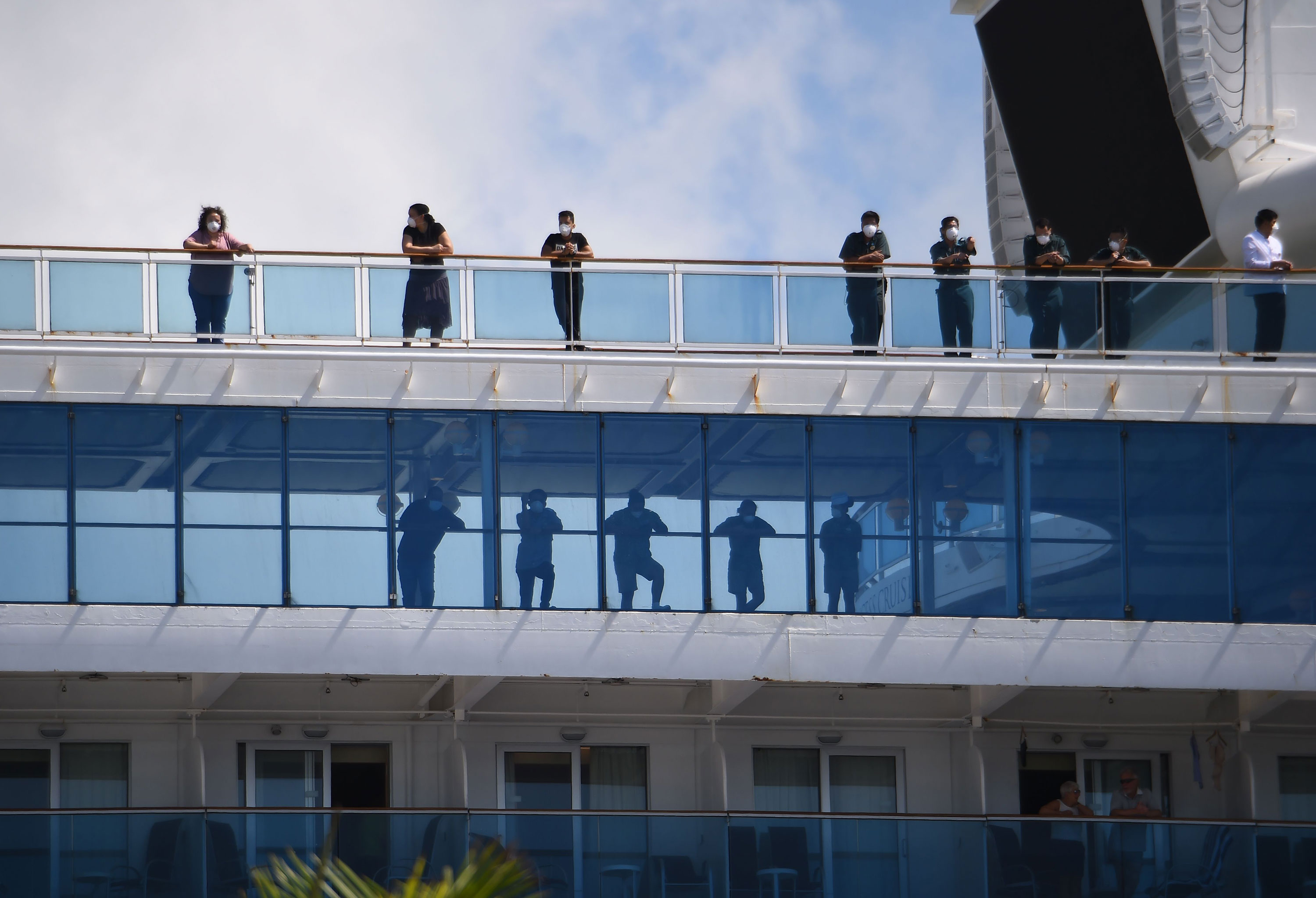 Passengers look out from the deck of the Coral Princess cruise ship as it docks in Miami, Florida, on April 4.