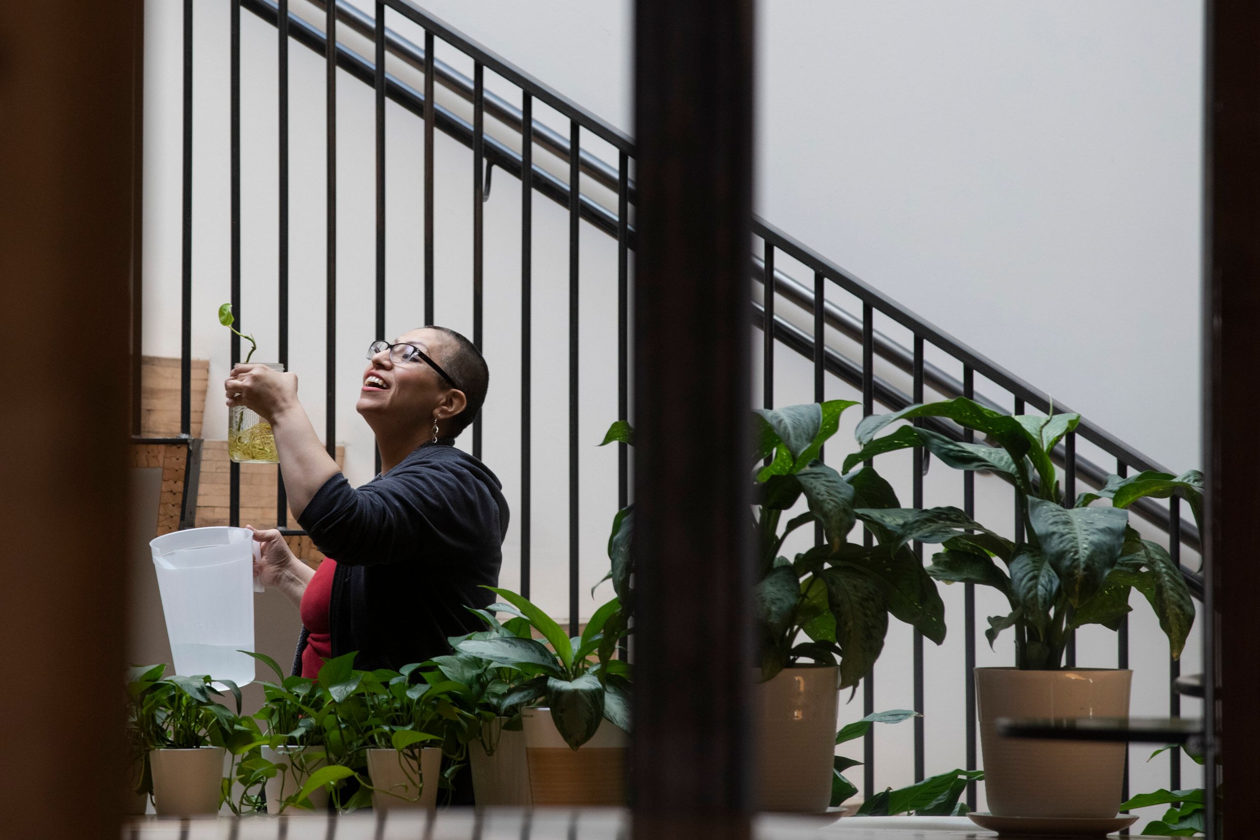 Ezzie Dominguez waters plants left behind by fellow employees at her day job as a building manager on March 31, 2020, in Denv