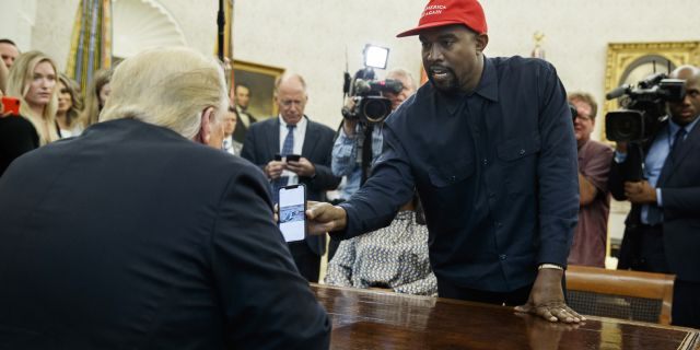 Rapper Kanye West shows President Donald Trump a photograph of a hydrogen plane during a meeting in the Oval Office of the White House, Thursday, Oct. 11, 2018, in Washington.