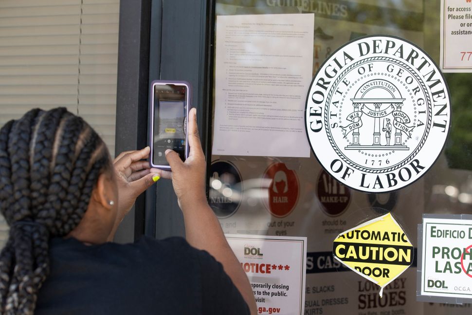 Arnashia McCain uses her phone to copy phone numbers posted on the locked doors of a Georgia Department of Labor office, May 