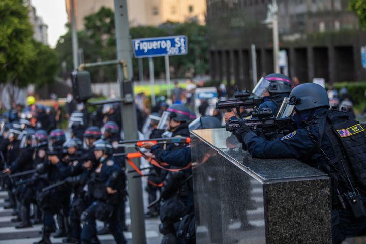 Police officers take position to shoot tear gas at demonstrators in downtown Los Angeles on Saturday.