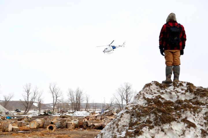 A protester watches a law enforcement helicopter circle the main opposition camp against the Dakota Access oil pipeline near 