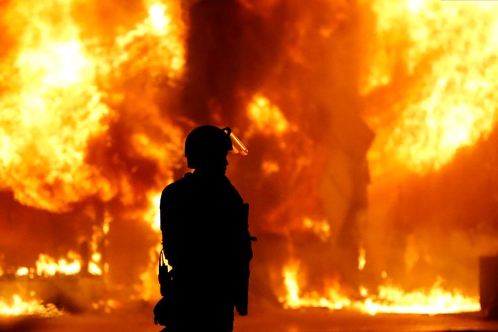A Minneapolis Police officer stands near a structure fire, Saturday, May 30, 2020, in Minneapolis. Protests continued followi