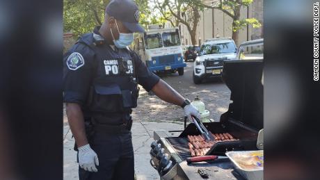 An officer in Camden County, New Jersey, grills hot dogs for one of the department&#39;s pop-up neighborhood parties. The city has reformed its police department to focus on de-escalating violence in the community.