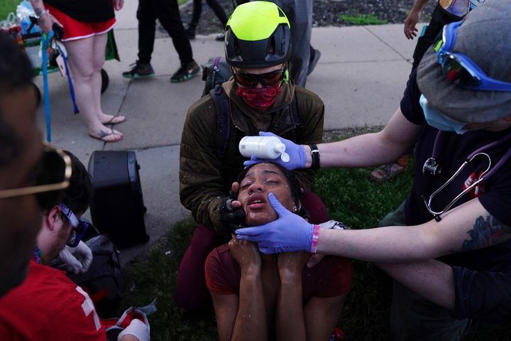 Citizen medics help a protester clear her eyes as police move in with tear gas against protesters near the Minneapolis Police