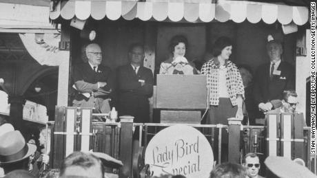 Lady Bird Johnson addressing a crowd from the back of a train during her whistle-stop tour of South; daughter Lynda Bird Johnson accompanies her. 