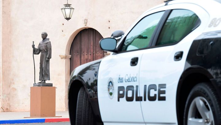A police vehicle parks near a statue of Junipero Serra in front of the San Gabriel Mission in San Gabriel, California, on Sun