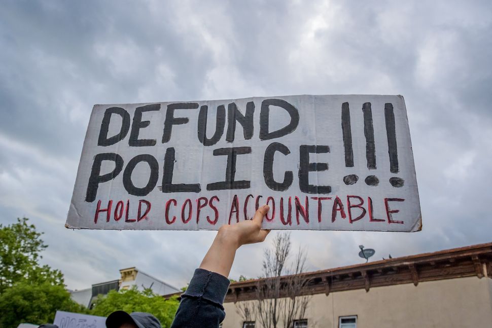 A participant holding a "Defund Police" sign at a protest. Hundreds of protesters flooded the streets of Crown Heights in Bro