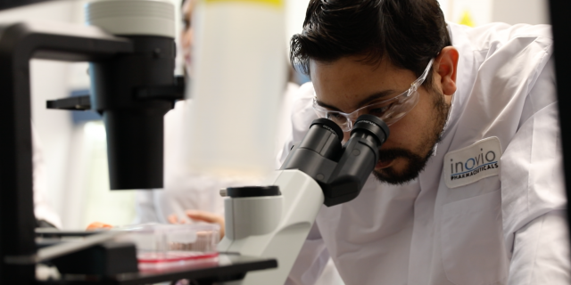 An INOVIO scientist peers into a microscope at the laboratory. (Photo courtesy of INOVIO Pharmaceuticals)
