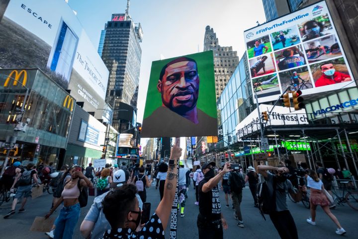 People protesting police brutality walk through Times Square with a portrait of George Floyd.&nbsp;