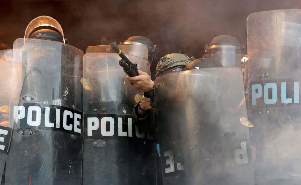 A police officer fires rubber bullets at protesters during a demonstration next to the city of Miami Police Department on May