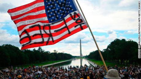 A man waves an American flag with the words &quot;Not Free&quot; painted on it as he takes part in a Juneteenth march and rally in front of Washington Monument in Washington, DC, on June 19, 2020. 