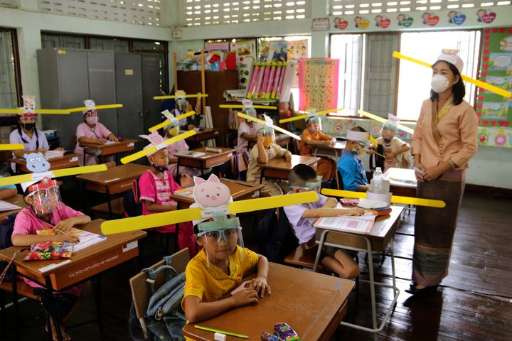 A teacher and students wearing hats designed to help them practice social distancing at a school in Thailand.&nbsp;