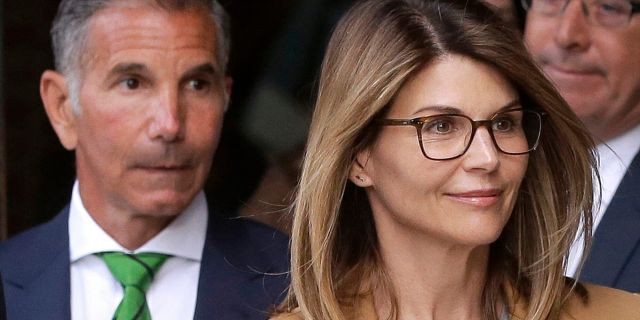 FILE - In this April 3, 2019, file photo, actress Lori Loughlin, front, and her husband, clothing designer Mossimo Giannulli, left, depart federal court in Boston after a hearing in a nationwide college admissions bribery scandal.