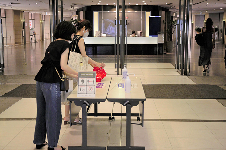 People wearing face masks wash their hands with hand sanitizer at an entrance of a shopping mall on July 11, in Tokyo.