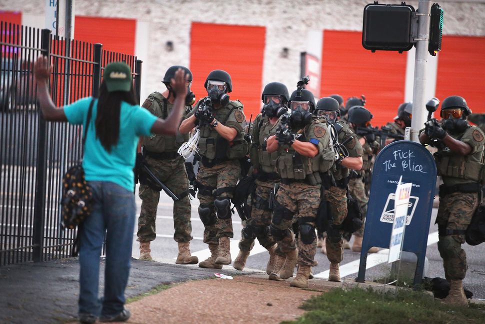 Police officers force protesters from the business district into nearby neighborhoods in Ferguson on Aug. 11, 2014.