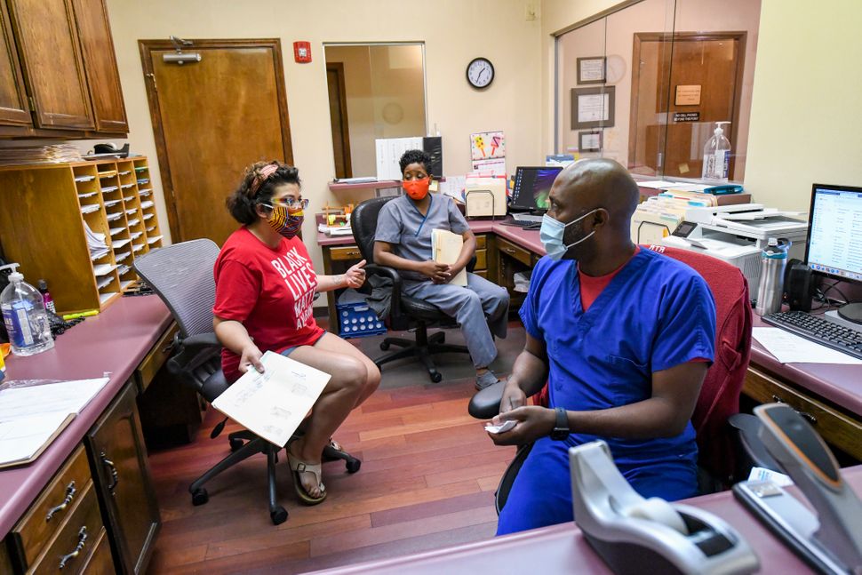 Amanda Reyes, center, talks with medical team manager Alesia Horton, left, and office manager Chadric Jackson in the front of